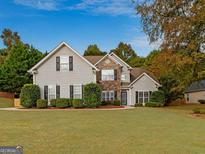 Charming two-story home featuring a combination of stone and vinyl siding, surrounded by mature trees and a well-maintained lawn at 228 Otter Cir, Fayetteville, GA 30215