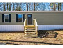 Mobile home exterior features a green facade, steps, and landscaping at 1979 Cardell Rd # 20, Austell, GA 30168