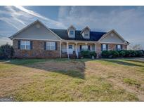 Charming brick and siding home with covered porch, dormers, and manicured landscaping at 25 Old Blue Pt, Social Circle, GA 30025