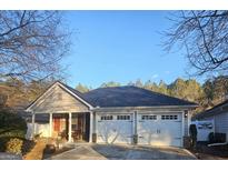 Charming single-story home boasts a two-car garage and a cozy front porch with seating at 117 Cottage Club Dr, Locust Grove, GA 30248