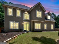 Charming two-story home at dusk features multiple windows and well-manicured lawn at 144 Wyckliffe Dr, Locust Grove, GA 30248