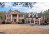 Beautiful brick home featuring a three-car garage, and classic architectural details at 125 Westgreen Way, Tyrone, GA 30290