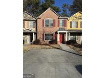 Charming brick townhome featuring a red front door and well-maintained landscaping at 7050 Galloway Pt, Riverdale, GA 30296