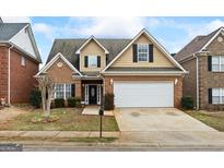 Charming two-story home featuring a brick facade, tan siding, and a spacious two-car garage at 243 Long Dr, Mcdonough, GA 30253