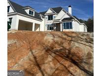 New construction home featuring white siding, black roof, and an attached two-car garage on a sloped lot at Lot 20 Platinum Rdg, Sharpsburg, GA 30277