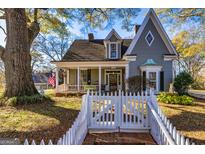 Charming two-story home with a welcoming front porch, landscaped yard, and a classic white picket fence at 86 Victoria Dr, Moreland, GA 30259