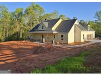 New construction home featuring light yellow siding, a dark gray roof, and an attached garage in a wooded area at Lot C Montannas Way, Moreland, GA 30259