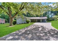 Charming single-story home with a long driveway and a covered carport surrounded by mature trees and lush greenery at 3403 Dodson Ter, East Point, GA 30344