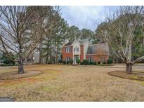 Charming two-story red brick home with a well-manicured lawn and mature trees surrounding the property at 500 Nicole Ct Se, Conyers, GA 30094