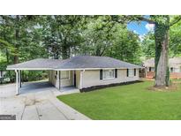 Charming ranch home with a lush lawn, carport, and mature trees surrounding the property at 1761 Carter Cir, East Point, GA 30344