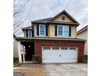 Two-story home featuring a brick facade, yellow siding, black shutters and a two-car garage at 2517 Oakleaf Rdg, Lithonia, GA 30058