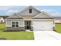 Charming one-story home featuring a two-car garage, black door, brick accents, and a well-manicured lawn at 1033 Claas Way, Locust Grove, GA 30248