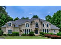 Beautiful home featuring stone accents, arched windows, manicured landscaping, and a well-maintained lawn at 709 Prestige Pt, Peachtree City, GA 30269