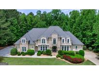 Stately home featuring stone and stucco exterior, lush landscaping, and a circular driveway at 709 Prestige Pt, Peachtree City, GA 30269