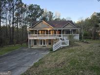 Charming two-story home featuring a large front porch, mature trees, and a spacious front yard at 9125 Spillers Sw Dr, Covington, GA 30014