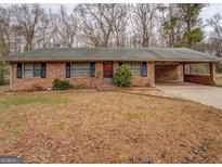 Charming brick ranch home featuring a covered carport and a neatly maintained front yard with mature trees at 155 Carole Dr, Oxford, GA 30054