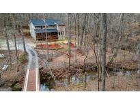 Charming home with a quaint wooden bridge and a serene creek, nestled among the bare trees of a wooded lot at 613 Rock Springs Pass, Dallas, GA 30157