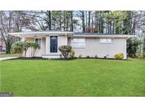 Charming single-story home featuring a well-manicured lawn and tidy landscaping at 3696 Aldea Dr, Decatur, GA 30032