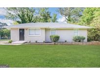 Charming one-story brick home with a well-manicured green lawn and landscaped garden bed at 3711 Tulip Dr, Decatur, GA 30032