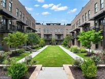 Inviting courtyard surrounded by brick townhomes, featuring a lush lawn and manicured landscaping at 1028 Robert Smalls Way, Atlanta, GA 30318