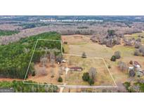 Expansive aerial view of property featuring charming home, large workshop, open land, and partial tree coverage at 62 Honey Ln, Mcdonough, GA 30252