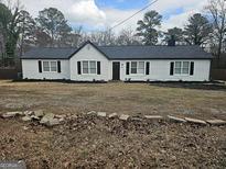 Charming single-story home featuring white siding, black shutters, and well-maintained landscaping at 3930 W Side Pl, Ellenwood, GA 30294