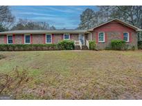 Charming brick home with red shutters, complemented by a well-maintained lawn and inviting front entrance at 308 Tulipwood Sw Cir, Conyers, GA 30094