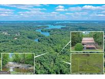 Stunning aerial view of the lakefront property with house, waterfall, and 34 acres of lush landscape at 5200A Burruss Mill Rd, Cumming, GA 30041