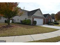 Charming single-Gathering home featuring a two-car garage and a well-maintained front lawn with a tree showing beautiful fall colors at 410 Mockingbird Dr, Loganville, GA 30052