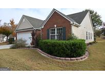 Charming brick home with a manicured lawn, trimmed hedges, and an attached two-car garage at 410 Mockingbird Dr, Loganville, GA 30052