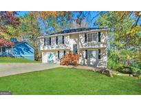 Two-story home featuring a wooden porch, attached garage, and lush green lawn at 5743 Rock Rd, Union City, GA 30291
