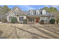 Charming single-Gathering home with stone accents, three dormer windows, and a bright red front door at 115 Foxford Run, Tyrone, GA 30290