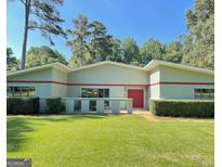 Single story home with a vibrant red front door, manicured lawn and mature landscaping at 225 Banks Rd, Fayetteville, GA 30214