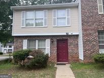 Charming townhome with brick and siding, featuring white shutters and a red front door at 923 Regal Path Ln, Decatur, GA 30030