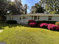 Charming single-story home with a well-manicured lawn and vibrant azalea bushes at 47 Elm St, Hampton, GA 30228