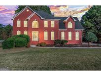 Beautiful brick home with manicured lawn and professional landscaping at sunset at 176 Fairoaks Cir, Stockbridge, GA 30281