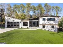 Contemporary home featuring a lush front lawn, dark framed windows, and a two-car garage at 4217 Paces Ferry Se Rd, Atlanta, GA 30339