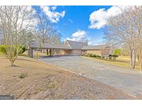 Sprawling home with a large driveway and unique covered parking area, set against a blue sky at 240 Sandy Lake Cir, Fayetteville, GA 30214