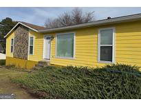 Charming yellow home with stone accents and landscaped front yard for curb appeal at 3796 Saddle Ridge Dr, Snellville, GA 30039