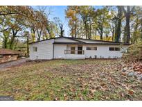 Charming white brick home featuring black trim and mature trees at 2544 Overlook Dr, East Point, GA 30344