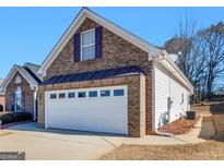 A two-car garage door on a brick home under a clear blue sky at 509 Carleton Pl, Locust Grove, GA 30248