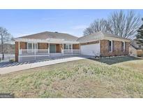 Charming brick home with white pergola, covered porch and nicely manicured lawn at 205 Castlewood Rd, Tyrone, GA 30290