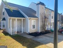 Charming townhouse featuring a covered porch, well-maintained landscaping, and neutral siding at 6365 Wellington Walk Way, Lithonia, GA 30058
