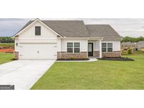 Charming home features white siding, brick accents, a two-car garage, and a well-manicured lawn at 1004 Claas Way, Locust Grove, GA 30248