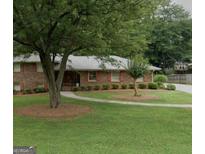 Charming brick home with mature trees, lush lawn, and well-manicured landscaping at 650 Foxcroft Se Cir, Marietta, GA 30067