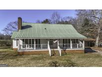 Charming single-story home featuring a green metal roof, brick foundation, and inviting front porch at 128 Turner Ln, Bowdon, GA 30108