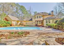 Backyard view of a large custom home featuring a pool and brick patio with manicured landscaping at 233 Spear Rd, Fayetteville, GA 30215