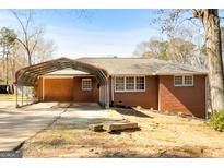 Charming single-story brick home featuring a covered carport, established landscaping, and a spacious front yard at 623 Swan Lake Rd, Stockbridge, GA 30281