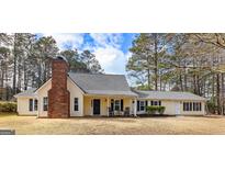 Charming one-story home with yellow siding, brick chimney and rocking chairs on the front porch at 108 Everhill, Peachtree City, GA 30269
