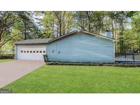 Single-story home featuring a clean-looking garage, a deck, and is surrounded by mature trees at 3756 Bright Star Rd, Douglasville, GA 30135